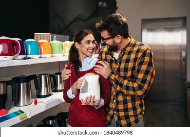 Young Couple Buying Electric Kettle For Their Home In Appliances Store.
