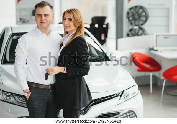 Young couple byuing\
a car in a car showroom