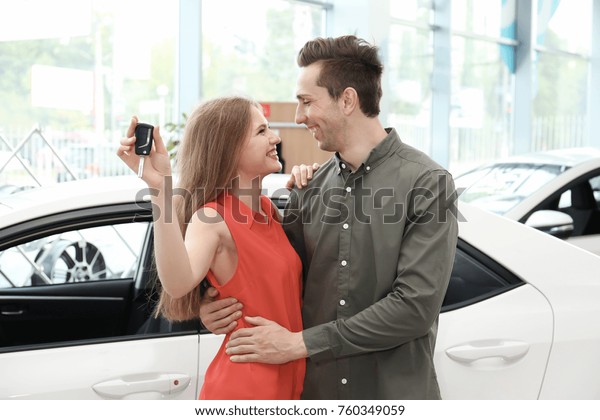 Young couple with car key in\
salon