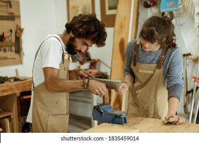 Young Couple Of Carpenter Working And Crafting With Wood In A Workshop Building Furniture For Interior Design. Young Couple Entrepreneurs Running A Small Business In A Carpentry. Business People.