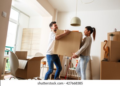 Young couple carrying big cardboard box at new home.Moving house. - Powered by Shutterstock