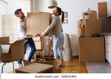 Young couple carrying big cardboard box at new home.Moving house. - Shutterstock ID 568241401