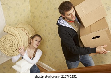 Young Couple Carrying Cardboard Boxes And A Mattress