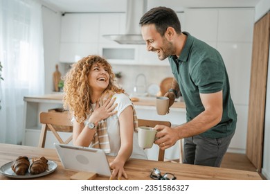 Young couple caucasian man and woman husband and wife enjoy cup of tea or coffee in the morning at home happy smile daily morning routine real people - Powered by Shutterstock