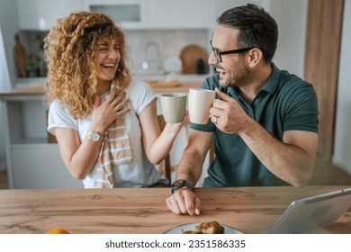 Young couple caucasian man and woman husband and wife enjoy cup of tea or coffee in the morning at home happy smile daily morning routine real people - Powered by Shutterstock