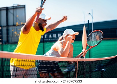 Young couple celebrate winning the point in tennis on outdoor court.	 - Powered by Shutterstock