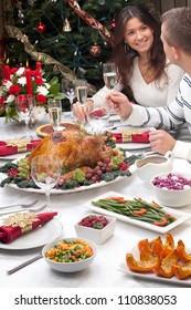 Young Couple Celebrates Christmas Turkey Dinner By The Christmas Tree.