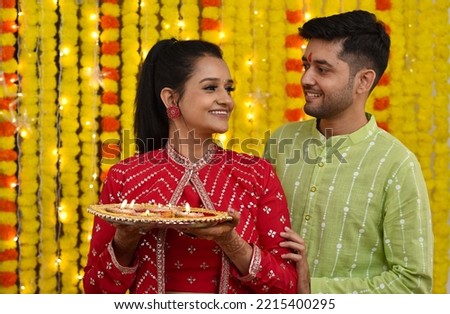 Young couple celebrating diwali ,holding plate of diya,sweets