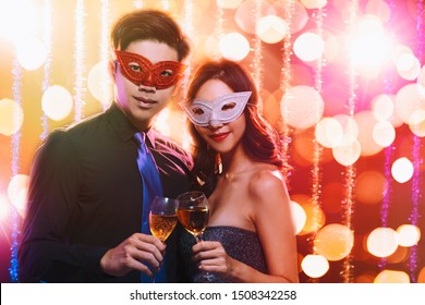 Young Couple Celebrating New Year And Drinking Champagne On Masquerade Party