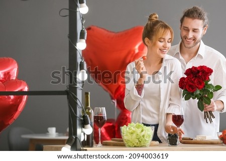 Young couple celebrating Valentine's Day while cooking festive dinner at home