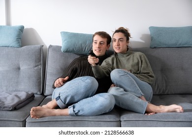 Young Couple Channel Surfing On  Tv While Sitting On Couch.