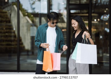 Young couple checking items inside shopping bags outside a retail store, representing modern consumer lifestyle, post purchase behavior, and shopping satisfaction in urban environment.