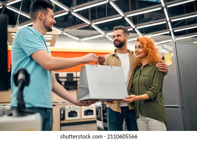 A Young Couple At The Checkout Picking Up A Purchase From A Salesperson In A Home Appliances And Electronics Store.