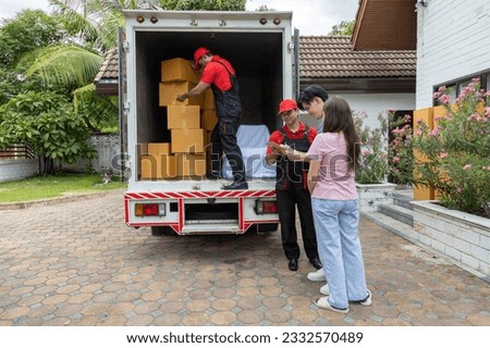 Young couple checks with two movers unloading boxes and furniture from a pickup truck