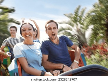 Young couple cheering on amusement park ride