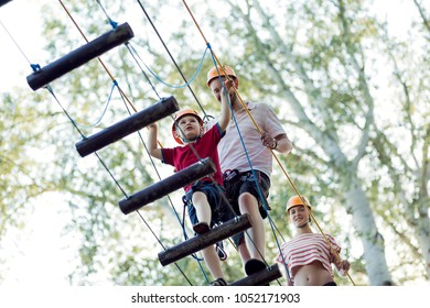 A Young Couple With A Child Walking On A Rope Bridge With Insurance. The Concept Of Active Family Rest, Spot