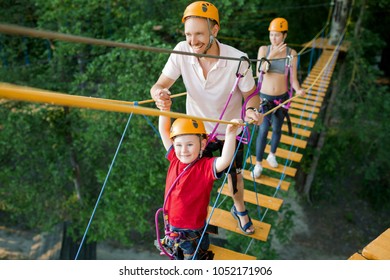 A young couple with a child walking on a rope bridge with insurance. The concept of active family rest, spot - Powered by Shutterstock