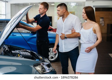 A Young Couple Chooses A New Car At The Dealership And Consults With A Representative Of The Dealership. Used Cars For Sale. Dream Fulfillment