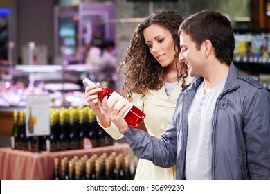 The young couple chooses a wine bottle in shop