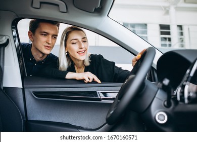 Young Couple Choosing A Car In A Car Show Room