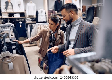 Young couple choosing clothes while shopping at the mall. Focus is on woman.  - Powered by Shutterstock