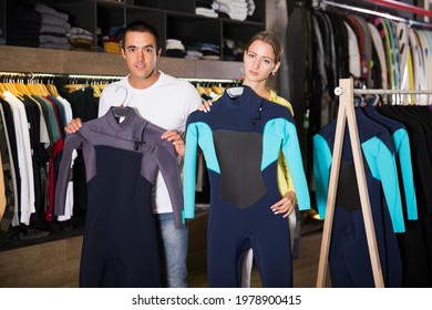 Young Couple Choosing Diving Suit In Clothing Store.