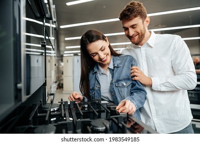 Young Couple Choosing New Gas Stove In Home Appliances Store