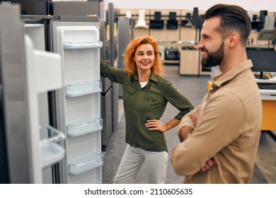 A Young Couple Is Choosing A New Refrigerator In A Home Appliances And Electronics Store. Buying A New Refrigerator.