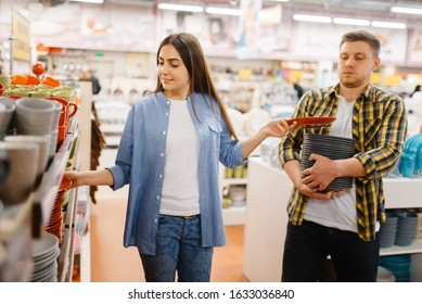 Young couple choosing plates in houseware store