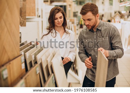 Young couple choosing tiles at building market