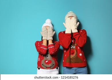 Young couple in Christmas sweaters and knitted hats on color background - Shutterstock ID 1214185276
