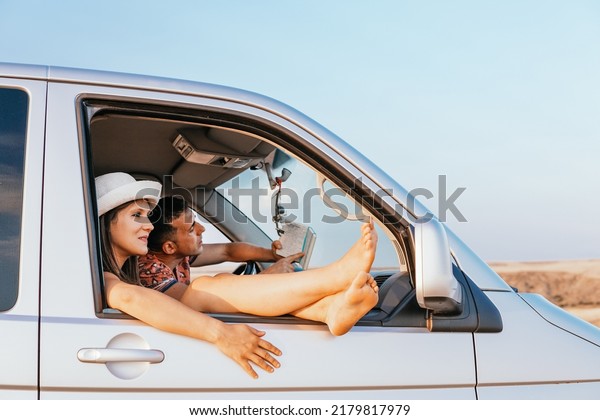 Young\
couple consisting of boy and girl traveling in their camper van\
prepared for road trips. The boy tries to interpret the notes to\
get to the location correctly. Van life\
concept.