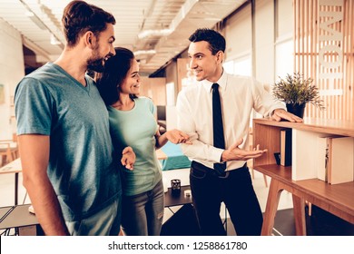 Young Couple Consulting With Furniture Seller. Customer And Buyer. Goods Showing. White Shirt. Bright Office. Sunny Day. Room Interior. Colors And Patterns. Tablet Screen. Family In Store.
