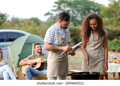 Young couple cooking food on barbecue grill outdoors - Powered by Shutterstock