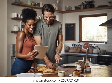 Young Couple Cooking Healthy Food Together Following Recipes Online On A Tablet, Step By Step. Happy, Cheerful And Smiling Husband And Wife Making Dinner In The Kitchen At Home.