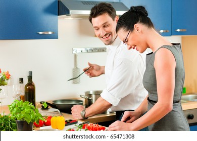 Young Couple Cooking - Man And Woman In Their Kitchen At Home Preparing Vegetables For Salad And Pasta Sauce