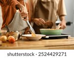 Young couple cooking spaghetti in a cozy kitchen. People, food and domestic life concept