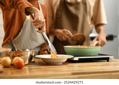 Young couple cooking spaghetti in a cozy kitchen. People, food and domestic life concept - Powered by Shutterstock