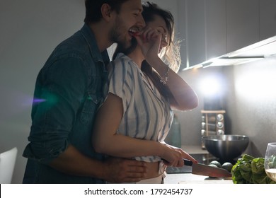 Young Couple Cooking Tasty Dinner Together In A Kitchen At Evening