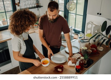 Young couple cooking together in a modern kitchen, mixing ingredients and cleaning dishes, showing teamwork and love in their domestic life - Powered by Shutterstock