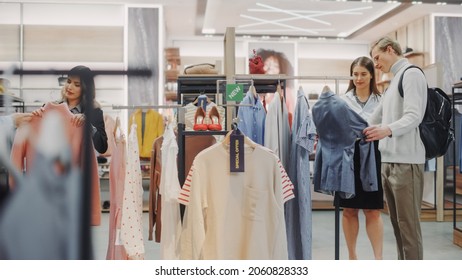 Young Couple Customers Shopping In Clothing Store, Retail Sales Associate Helps With Advice. Diverse People In Fashionable Shop, Choosing Stylish Clothes, Colorful Brand With Sustainable Designs