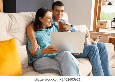 Young couple with cute Beagle dog and laptop at home - Powered by Shutterstock