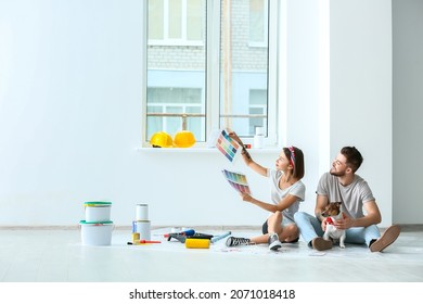 Young couple with cute dog and palette samples planning design of their new house - Powered by Shutterstock