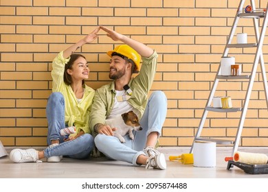 Young couple with cute dog resting during repair in their new house - Powered by Shutterstock