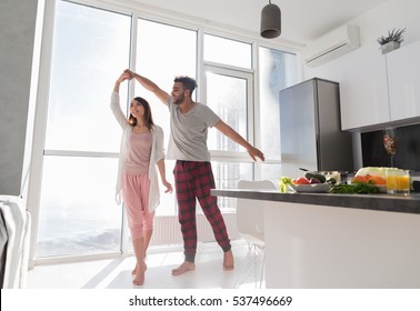 Young Couple Dancing In Kitchen, Lovely Asian Woman And Hispanic Man Modern Apartment With Big Windows Interior