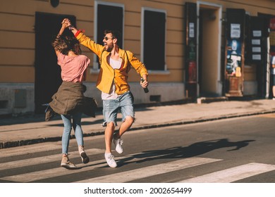 Young couple dancing on the street and holding bottles of beer - Shutterstock ID 2002654499
