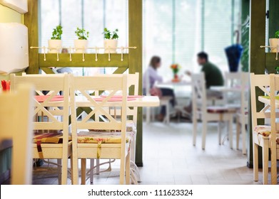 Young couple dating in stylish cafe. Primary focus on empty chairs.