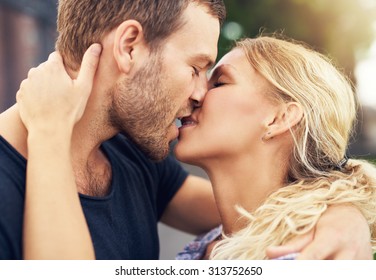 Young Couple Deeply In Love Sharing A Romantic Kiss, Closeup Profile View Of Their Faces