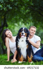 Young Couple With A Dog On The Grass In The Park