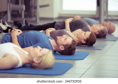 Young couple doing aerobics in a gym with a group of diverse people in a receding row, focus to the young man and woman in the foreground, health and fitness concept - Powered by Shutterstock